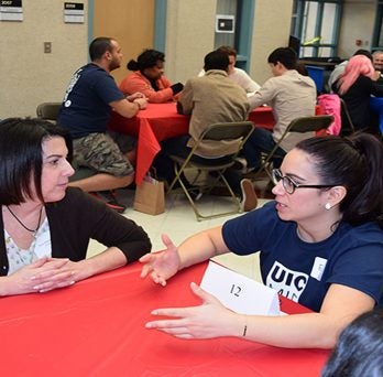 Students talking at tables
                  