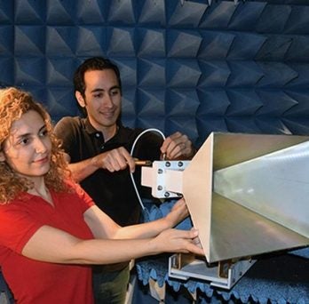 Seiran Khaledian and Farhad Farzami adjust an amplifier
                  