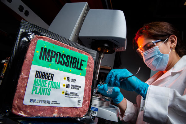 A package of plant-based meat next to a researcher using machinery