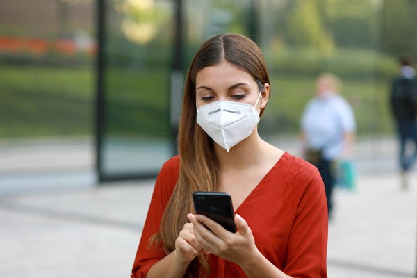 Person holding a cellphone and wearing a face mask