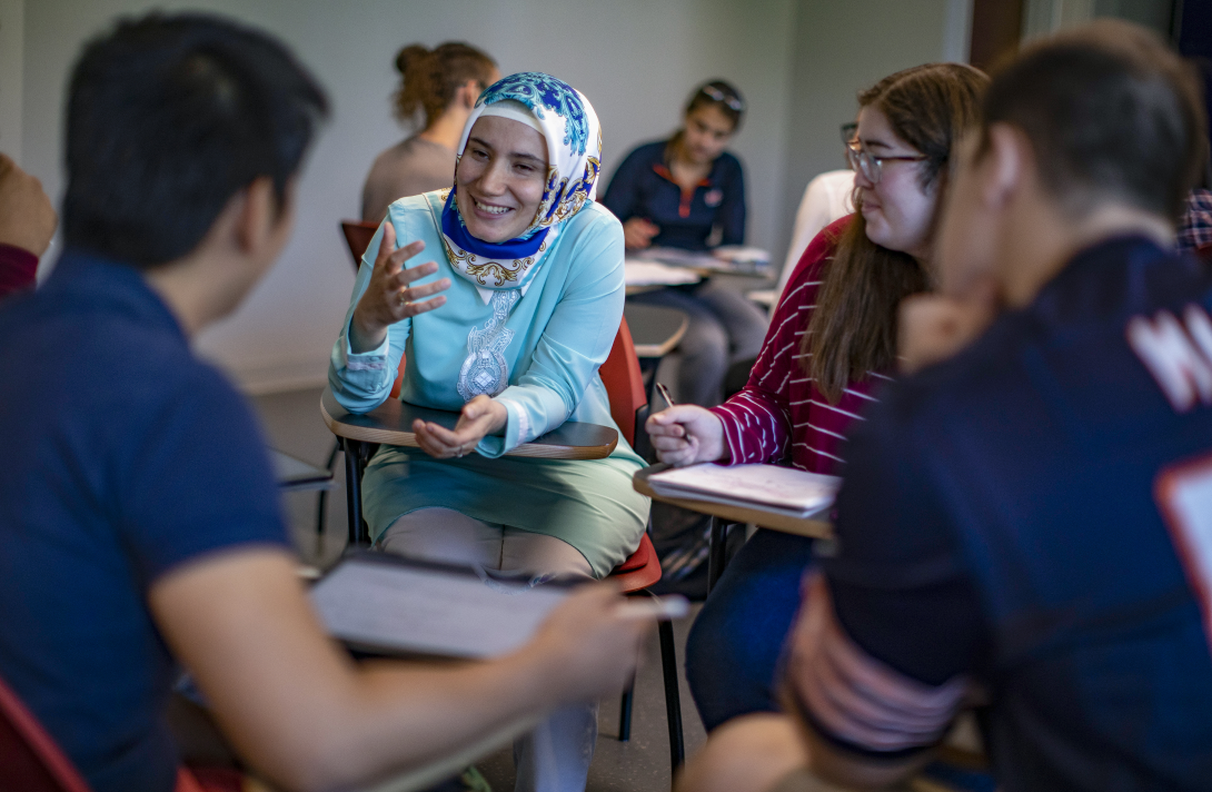 Bilgin sitting with students in class