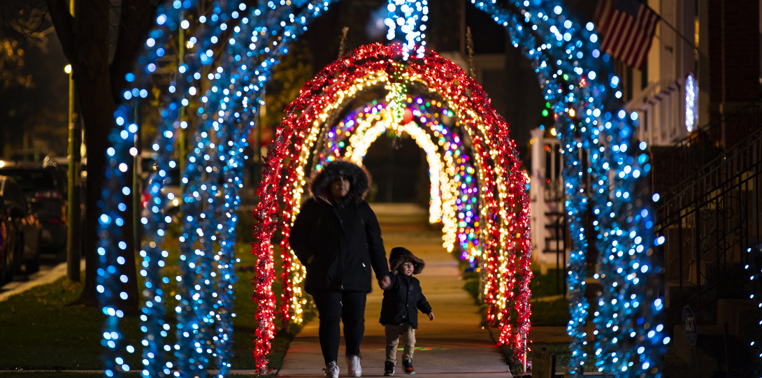 A woman and child walk through the Holiday lights in Irving Park
