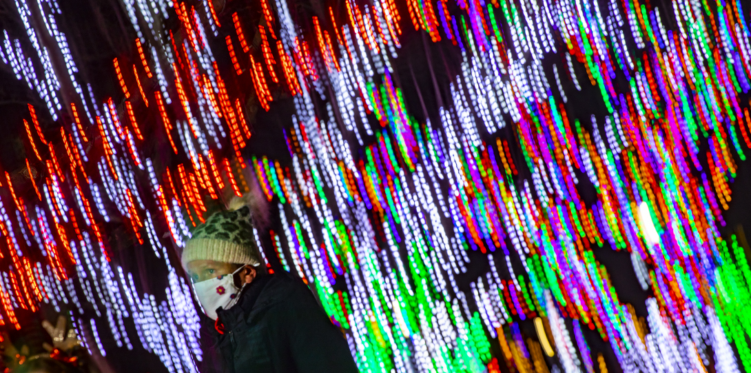 Woman walks under Hholiday themed lights in Lilacia Park