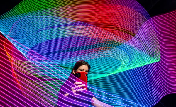 A female student with a cell phone amid rainbow laser lights