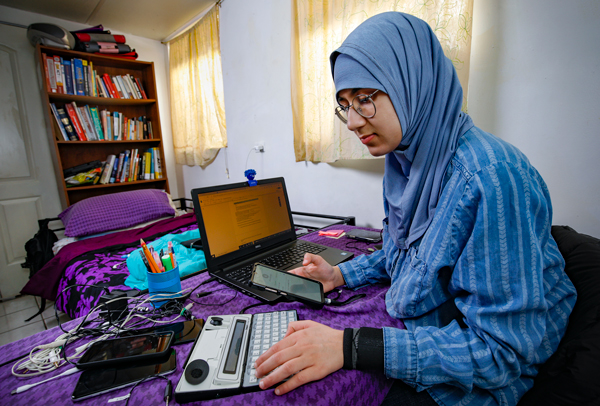 Dua Shehadeh works in her bedroom at home, performing testing procedures for consumer devices