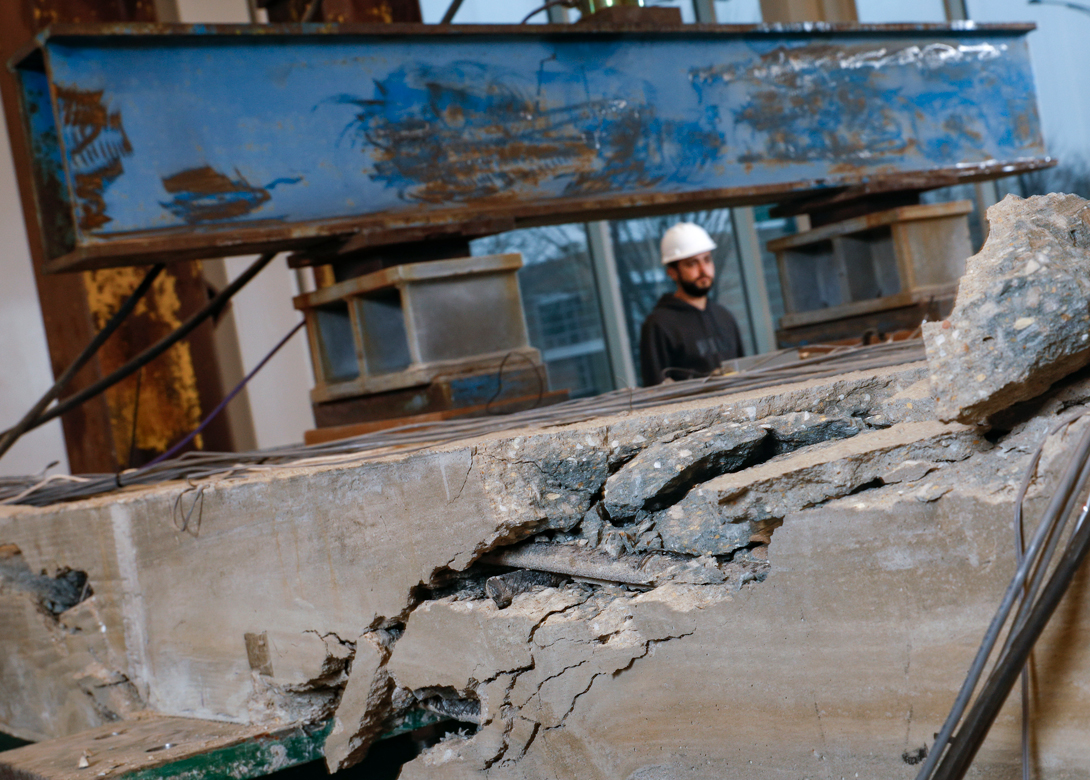A person in a hard hat inspecting damaged infrastructure