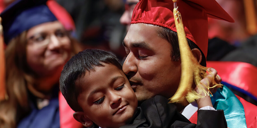 graduates kisses child at ceremony