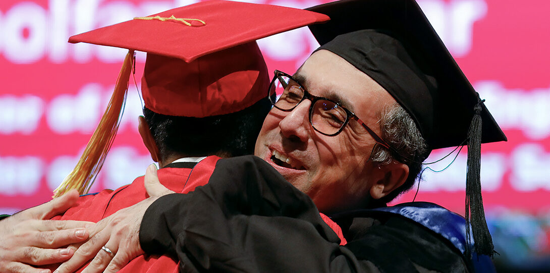 professor hugs student at ceremony