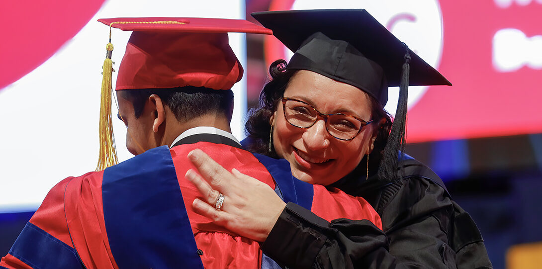 professor hugs students at ceremony