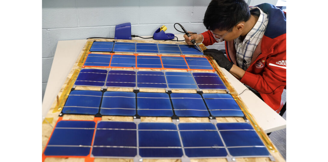 student solders solar panels on to board
