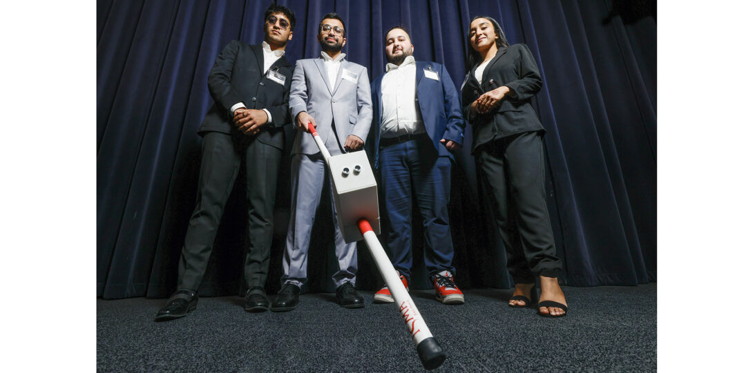 students pose with electronic cane for visually impaired
