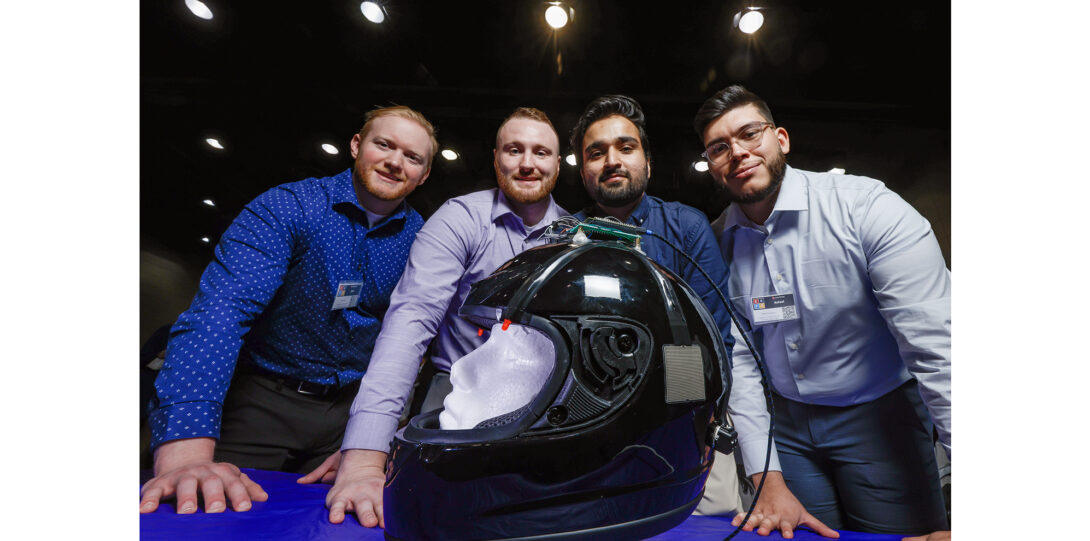 students pose with motorcycle helmet outfitted with electronic device