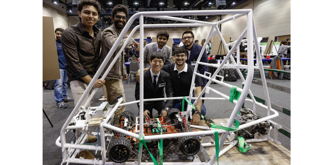 student poses with car frame