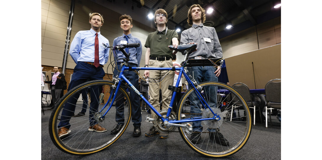 students pose with bicycle modified with electronic device