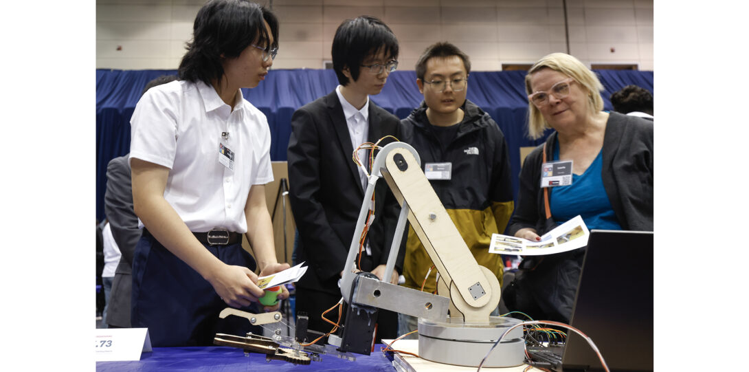 students listen to judge about their robotic arm project