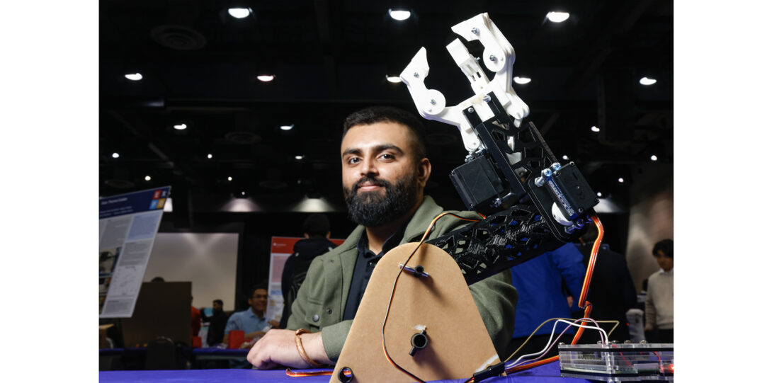 student poses with robotic hand