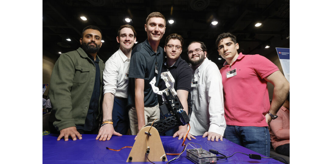 students pose with robotic arm