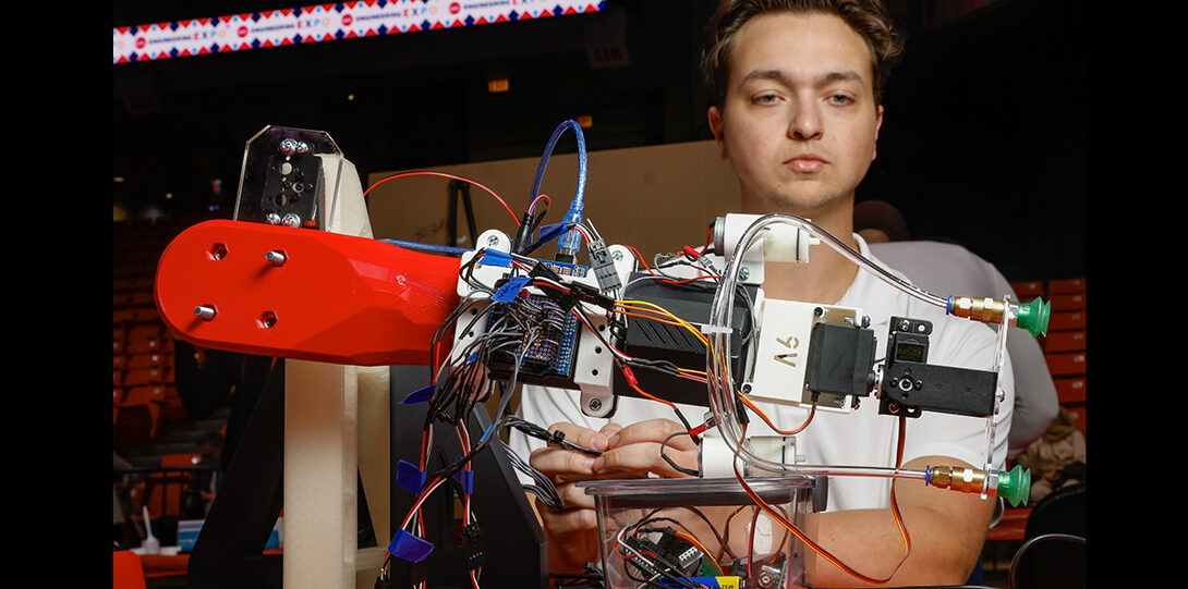 student photographed with controller moving robotic arm