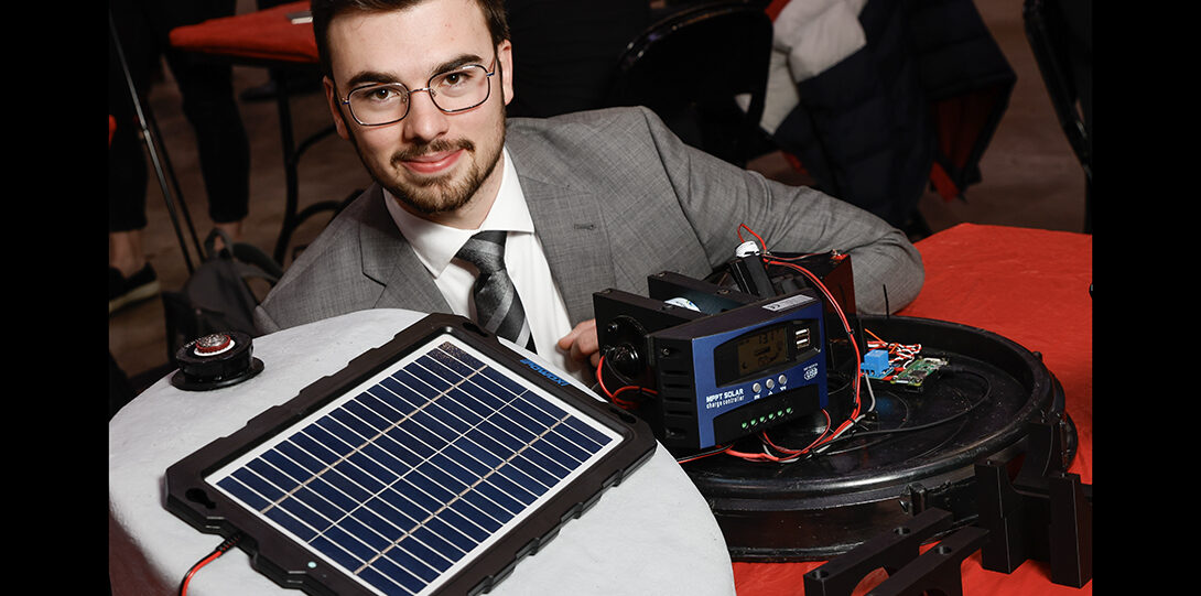 student photographed with solar panel and electronic equipment