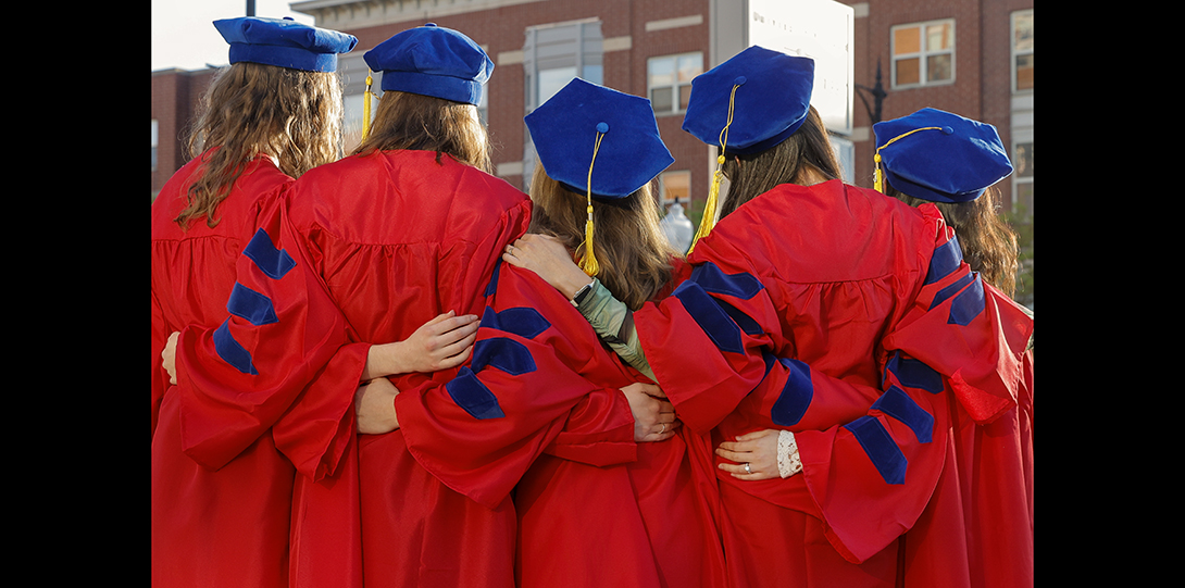 graduating students put their arms around each other for a photograph
