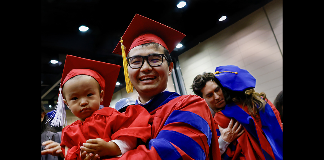 Father hold son at graduation ceremony