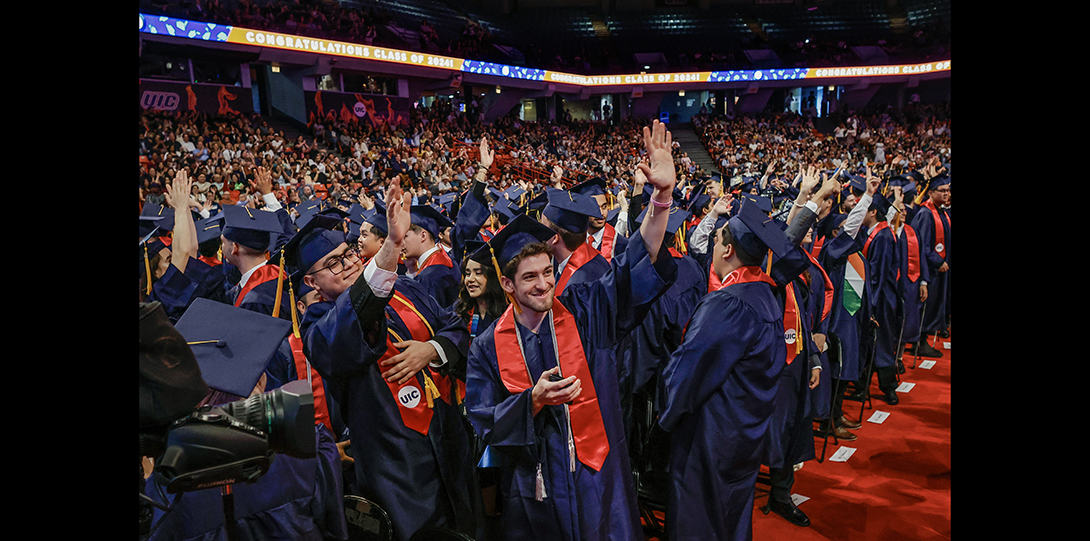 group of graduating students wave to the crowd