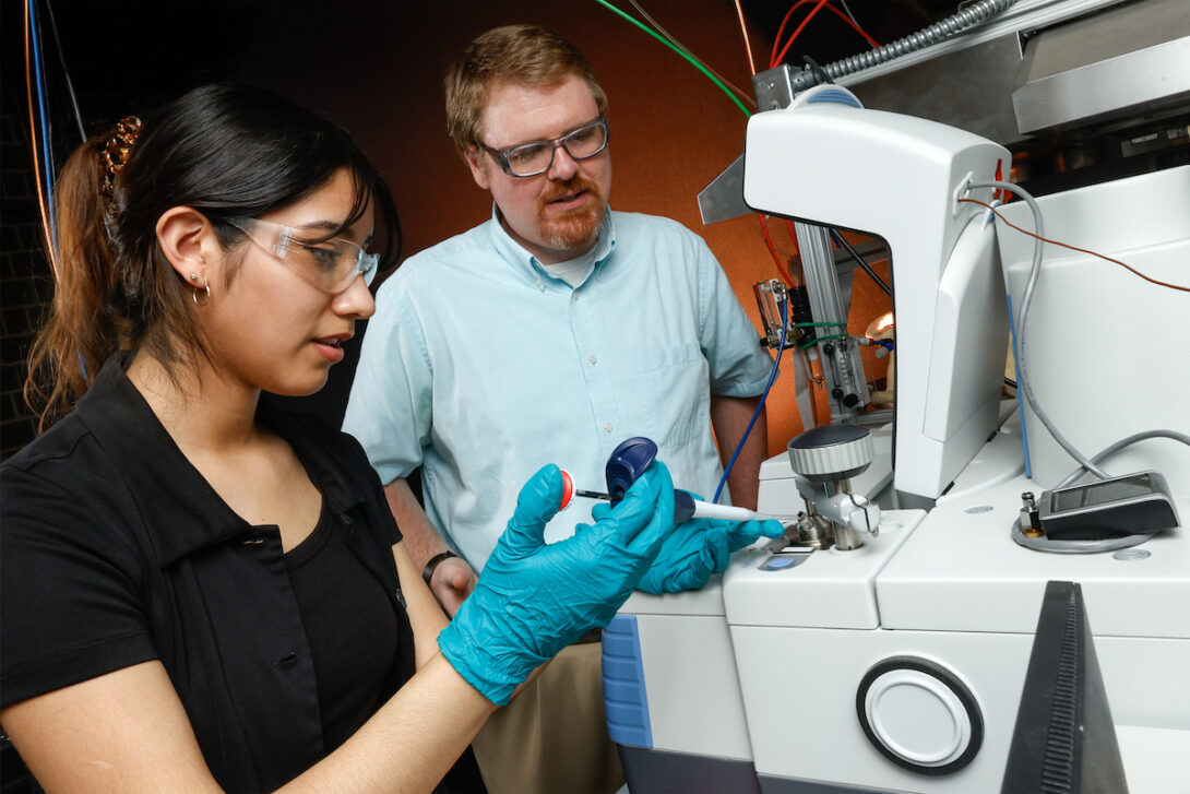 Associate Professor Patrick Lynch, right, and student Lizbeth Vasquez work with a machine acquiring spectra of fuels.