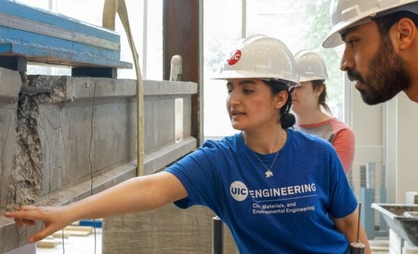 Student inspects damage to a concrete beam