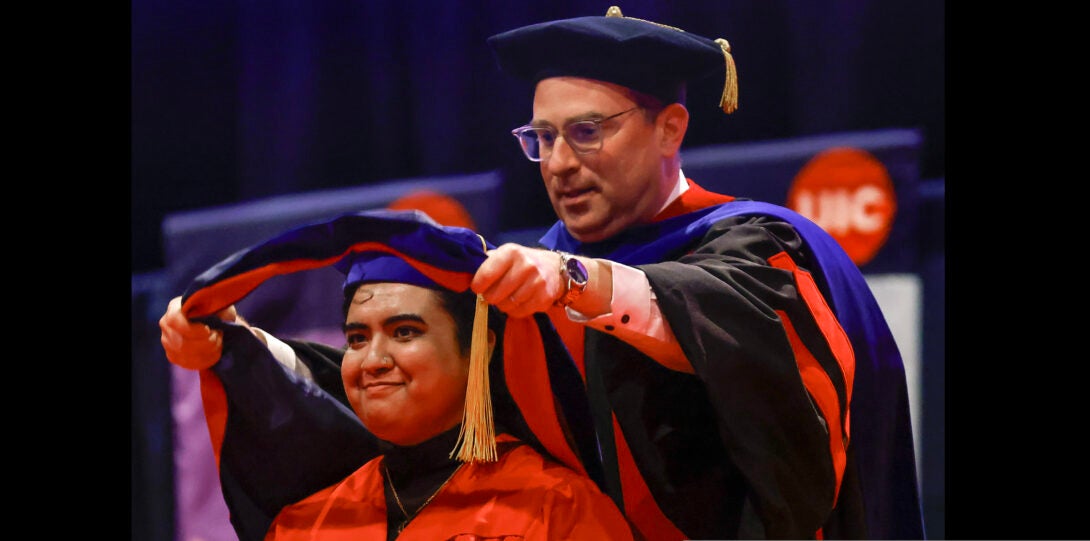 student receives ceremonial hooding from professor