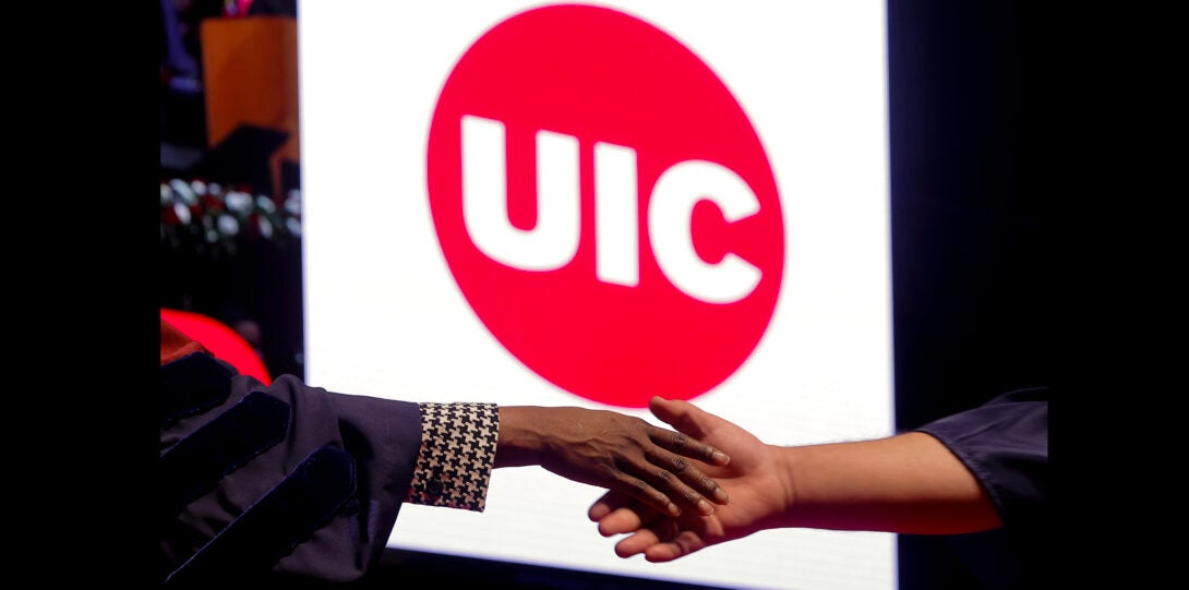 shaking hands with UIC logo in the background