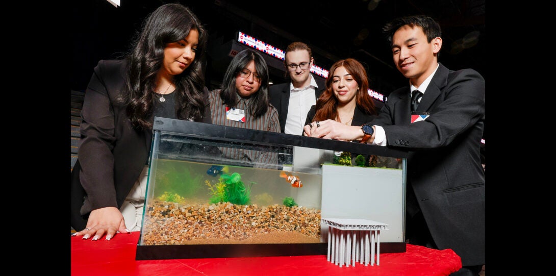 group of students demonstrate deisgn project built inside a fish tank