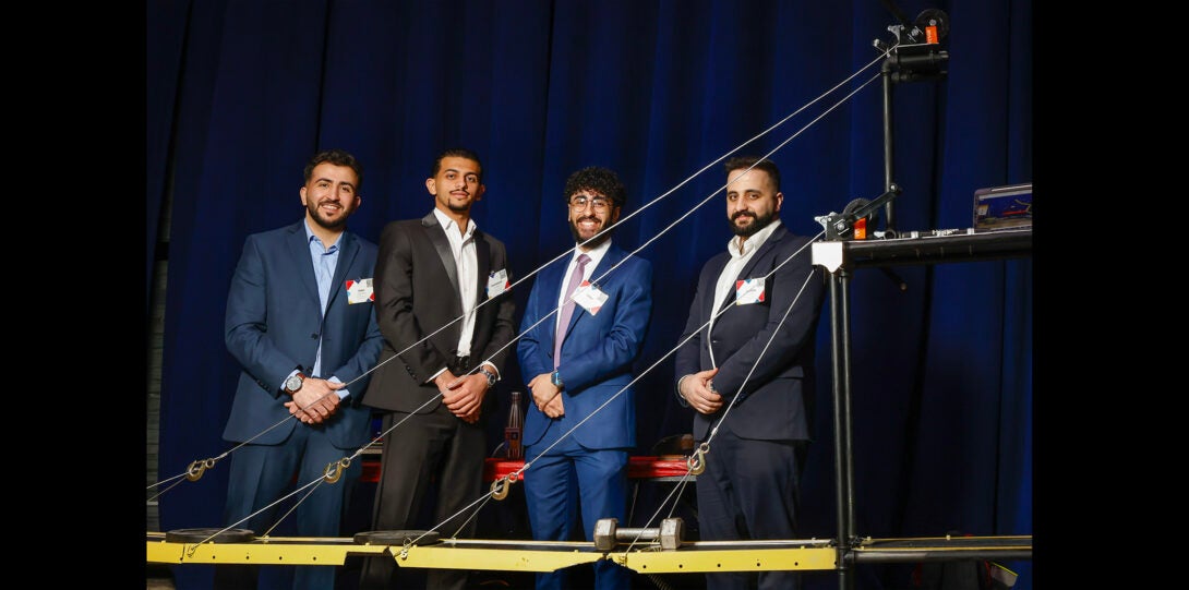 group of students pose with scale model of bridge