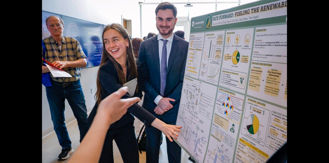 group of students explaining their project poster to judges