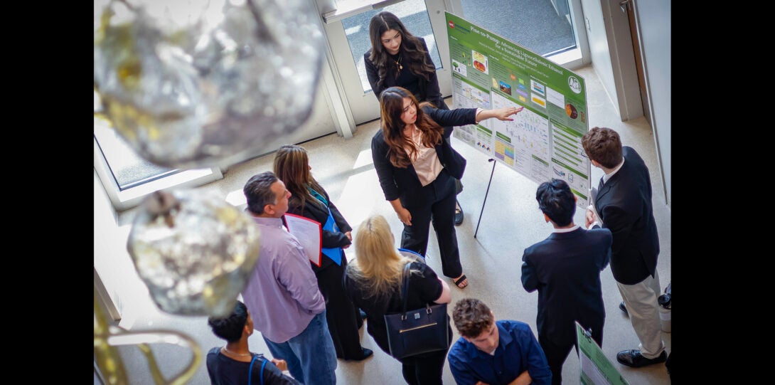overhead view of a group of students explaining their project poster to judges