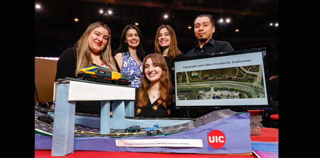 group of students pose with scale model of bridge
