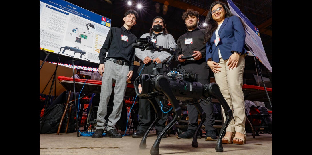 group of students pose for a photo with robot