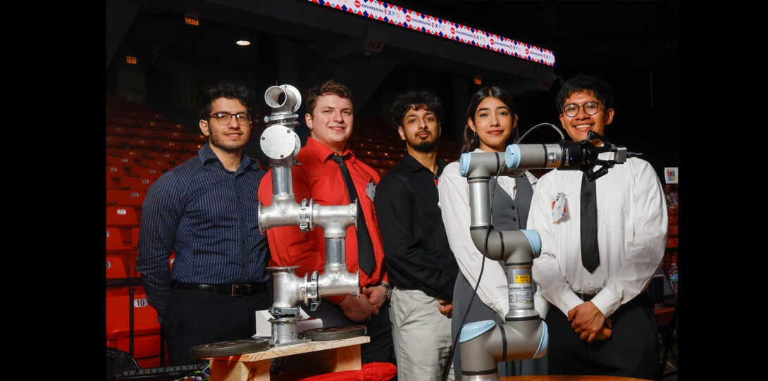 group of students pose for a photo with robotic arms